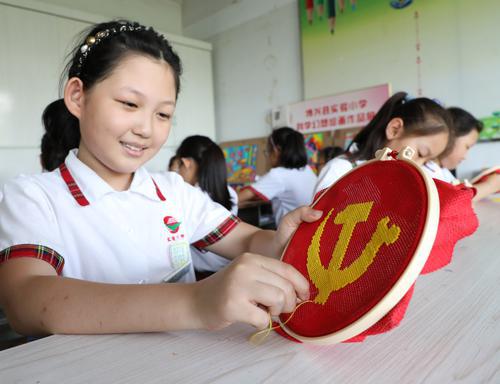 2021年6月22日,博兴县实验小学的小学生在认真绣党徽.