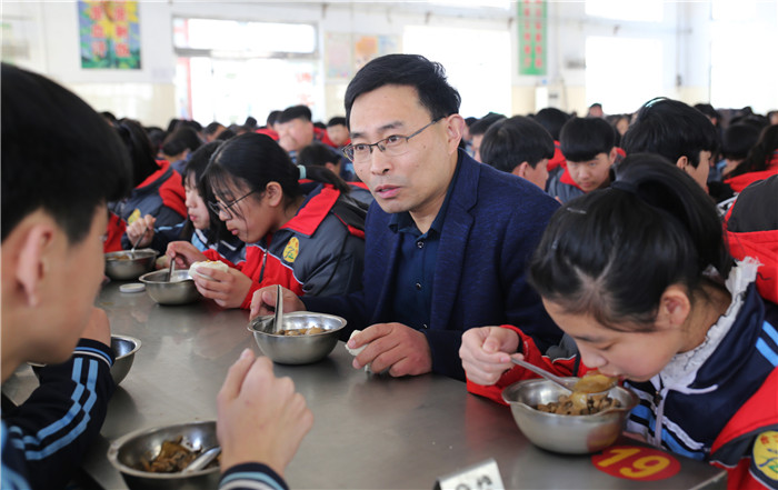 4月1日,邹平市台子镇初级中学校长陈晓东(右二)在学校食堂与孩子们