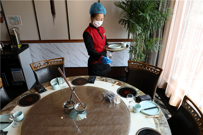 4月6日,在博兴县一家火锅饭店,一名服务员正在餐桌上摆放公筷公勺.