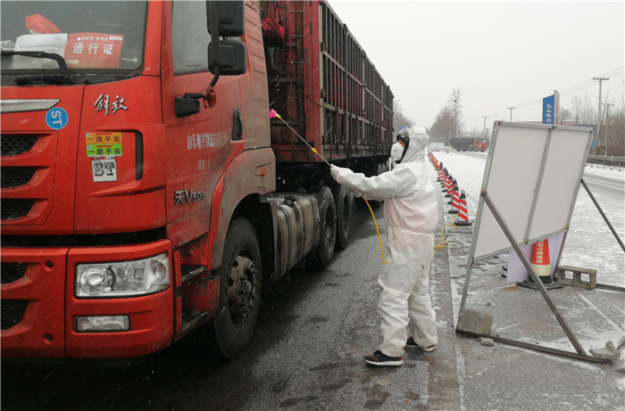 2月6日,邹平市长山镇志愿者雪天在道路交叉口为车辆消毒.